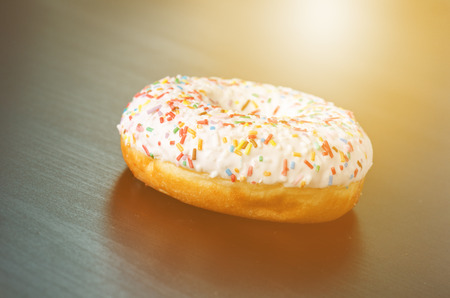 Donut with sprinkles and white iced. Donuts background. Cake and sweet. Food detail. Close upの写真素材