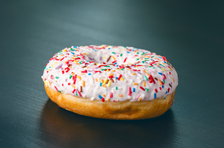 Donut with sprinkles and white iced. Donuts background. Cake and sweet. Food detail. Close upの写真素材