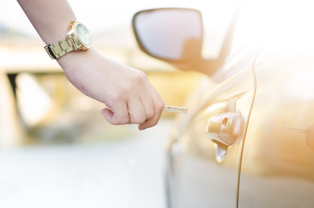 Woman with car key. Opening car door. Woman´s hand unlocking a door on a car. Sunlight. Transportation.の写真素材