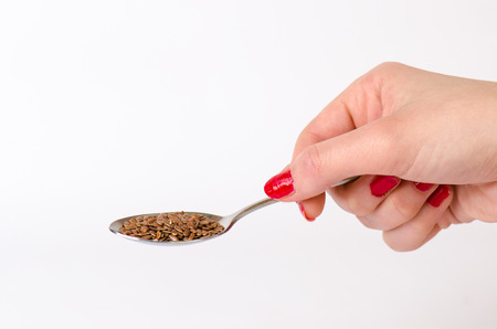 WomanÂ´s hand keep a spoon with seed. White background. Isolated. Macro. Agriculture.の写真素材