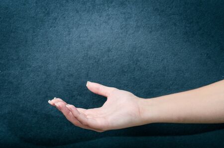 Woman show a gesture with hand. WomanÂ´s hand. Spasm hand. Dark blue background.の写真素材