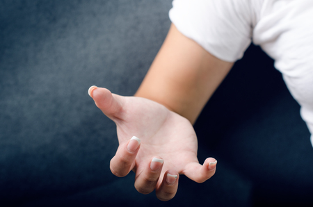 Woman show a gesture with hand. WomanÂ´s hand. Spasm hand. Dark blue background.