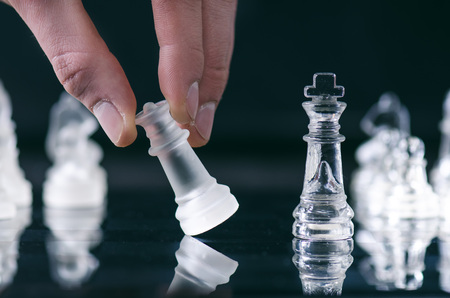 Hand of man keep a figure of chess. Chess business concept of victory. Chess figures in a reflection of chessboard. Game. Competition and intelligence concept.の写真素材