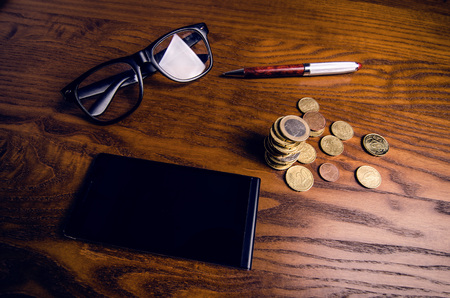 Concept of financial and economics. Smart phone, money, pen and glasses on a wooden table. Work in office. Investmentの写真素材