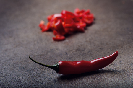 Chopped red chilli pepper on a black background. Spicy on a wooden spoon. Vegetable. Concept of hot food.の写真素材