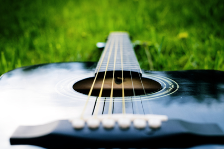 Detail of acoustic guitar on a grass. Natural background with flowers, grass and sun. Musical instrumentの写真素材