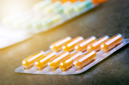 Medicines, supplements in a glass bottle. Pills spilling out from glass bottle. MedicineÂ´s background. Pharmacy. Close up of capsules. Pack of tablets on a black background.の写真素材