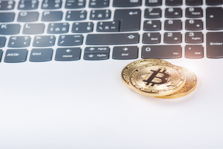 Bitcoin coins on a keyboard of white laptop. Computer. Investment situation. New virtual currency....