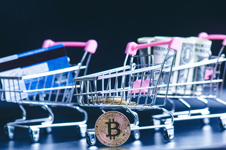 Bitcoin, bank card and money in a trolley on a black background. Concept of shopping and money. Cryptocurrency. Online shopping. Virtual currency and businessの写真素材