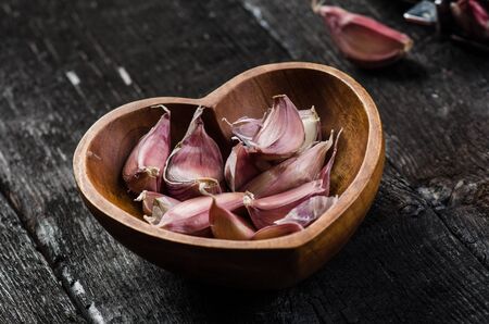 Cloves of garlic on a wooden black table. Fresh garlic bulb with iron garlic press. Vintage background. Farmer. Medicine and healthy. Traditional medicine.の写真素材