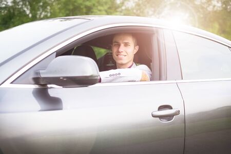 Young, happy, business man in the car. Man in a suits standing by the expensive, sport car. Successful young man.の写真素材