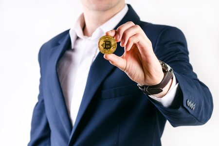 Young business man holding a bitcoin coin. White collar. Cryptocurrency symbol of bitcoin. Money and investment background.の写真素材