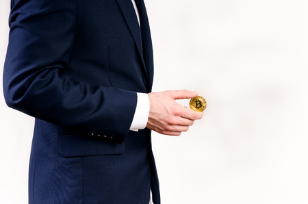 Young business man holding a bitcoin coin. White collar. Cryptocurrency symbol of bitcoin. Money and investment background.の写真素材