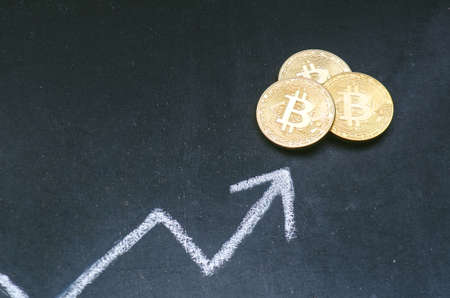 Crypto currency concept. Bitcoin golden coins on a blackboard with trade chart. Move up trend. Virtual currency. New virtual money.の写真素材