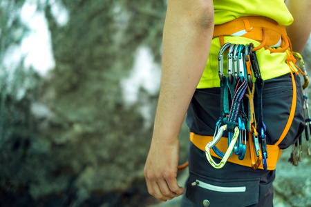 Detail of young man who preparing on a climb and standing a next to rock wall. Equipment for climbing on a man with copy space for a text.の写真素材