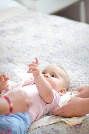 Young beautiful, adorable girl lying on a bed with white background. Parent and child are laughing and playing together. Cute baby and childhood concept.の写真素材