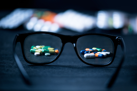 Pills, tablets focused in glasses on a black background. Pharmacy and medicine concept. Focused on a pharmaceutical industry. Different type of pills in blister,. Medicine and healthyの写真素材