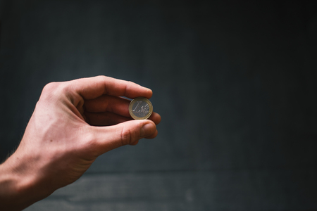 Man holding a coins. Euro currency on a black background. HandÂ´s of young man holding a money. Finance and banking concept. Black economy.の写真素材