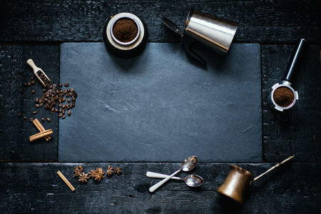 Concept - preparing of coffee. Coffee cup, mocha, coffee maker, roasted beans, spoons, turkisch cezve, biscuits and cardamom. Coffee background on a stone and black wood.の写真素材