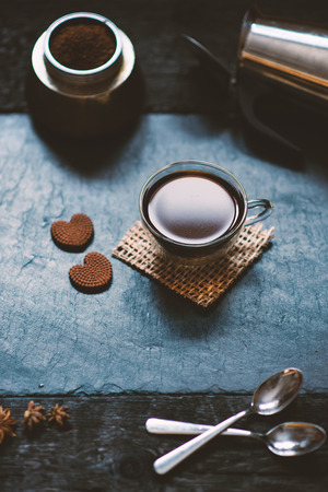 Concept - preparing of coffee. Coffee cup, mocha, coffee maker, roasted beans, spoons, turkisch cezve, biscuits and cardamom. Coffee background on a stone and black wood.の写真素材