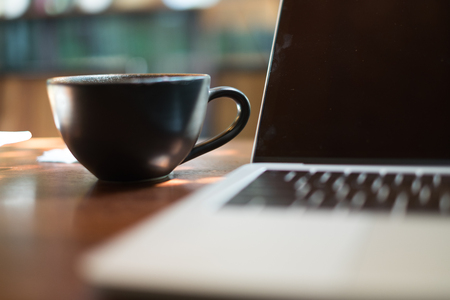 Select focus on hot a cup coffee blurred with notebook on wooden table blur backgroundの写真素材