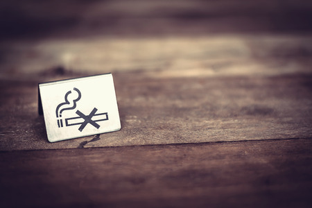 No smoking sign on wooden table. Image with vintage tone.の写真素材