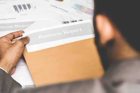 Businessman pulling out business report from document envelope.の写真素材