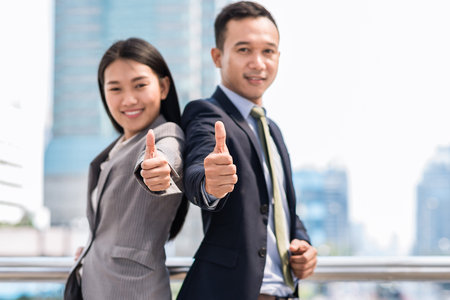 Young happy business Asian man and woman gesturing thumb up. Business success concept.の写真素材