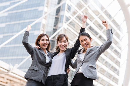 Happy young Asian businesswoman team arm up to celebrate their success outdoor in cityの写真素材