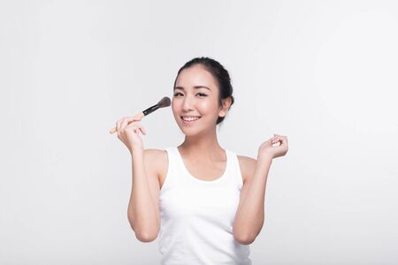 Portrait of attractive young Asian woman with beautiful skin holding brush for make up.の写真素材