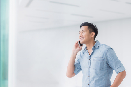 Portrait of Happy Asian man talking on a smartphone in building with copyspaceの写真素材