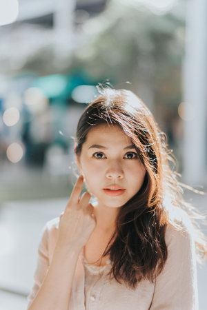 portrait of young beautiful Asian woman posing outdoor in sunlightの写真素材