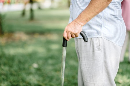 Cropped shot of an elderly senior man holding onto a cane in the park の写真素材