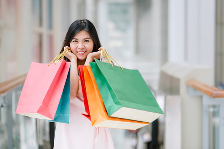 Happy Asian beautiful woman enjoying and smiling with colorful shopping bag in her both hand in mall. の写真素材