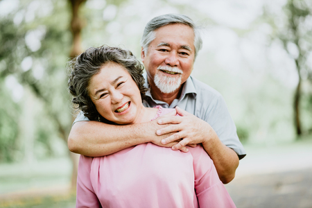 Happy smile senior Asian couple enjoying quality time at the park. A man embracing woman closely. success marriage life.の写真素材