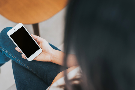 Back view of woman holding blank smartphone mobile mock up for advertising.の写真素材