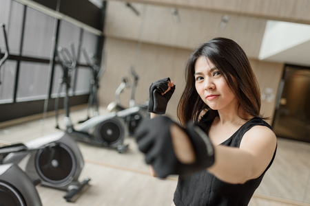 Asian woman training boxing exercise with gloves at gym punching to cameara.の写真素材