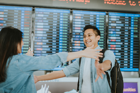 Happy Asian woman giving warm welcome hugging to her boyfriend after he return from abroad at an airport の写真素材