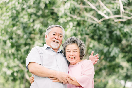 Happy Asian senior couple having a good time. They laughing and smiling while holding each other outdoor in the park.の写真素材