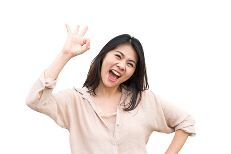 Happy Asian woman showing ok sign and looking at the camera isolated on white backgroundの写真素材