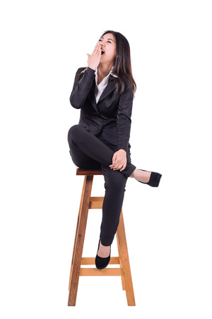 Happy young Asian businesswoman laughing while sitting on wooden chair isolated on white backgroundの写真素材