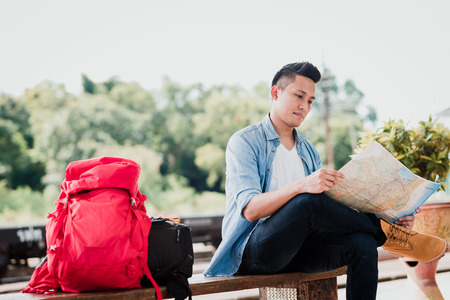 Asian traveler man using map searching for location at train stationの写真素材
