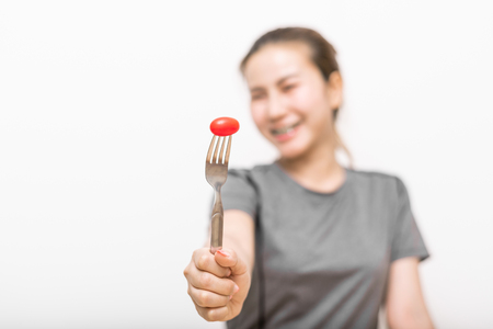 Smiling young woman presenting tomato on fork. dieting concept.の写真素材