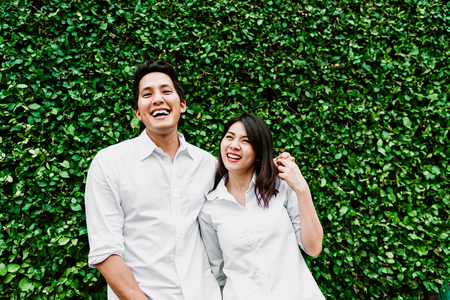 Happy Asian couple in love smiling and having fun while hugging outdoorの写真素材