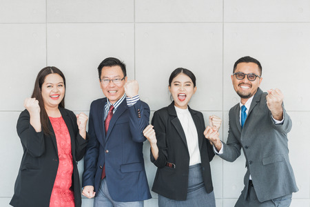 Happy Asian business people team celebrating success with arms upの写真素材
