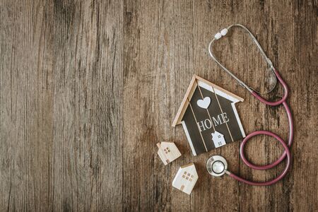 House model with stethoscope on wooden background. Home checking conceptの写真素材
