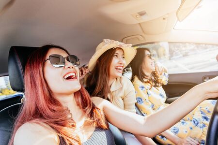 Three happy Asian girlfriends enjoying and having fun their road trip in car on vacation