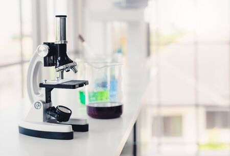 Microscope in labroatory with test tube and beaker in background