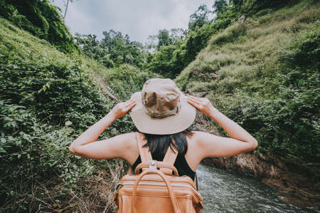 back view of travel woman with hand touching her hat feeling free and enjoying nature in mountain when hikingの写真素材