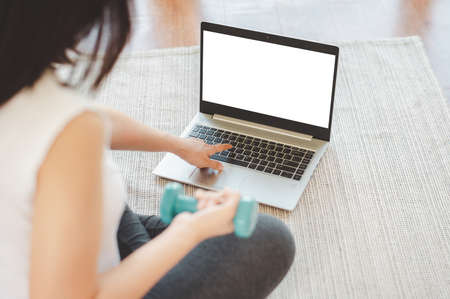 Asian woman doing plank exercise at home in a living room while watching online workout session from laptop. Fitness at home concept.の写真素材
